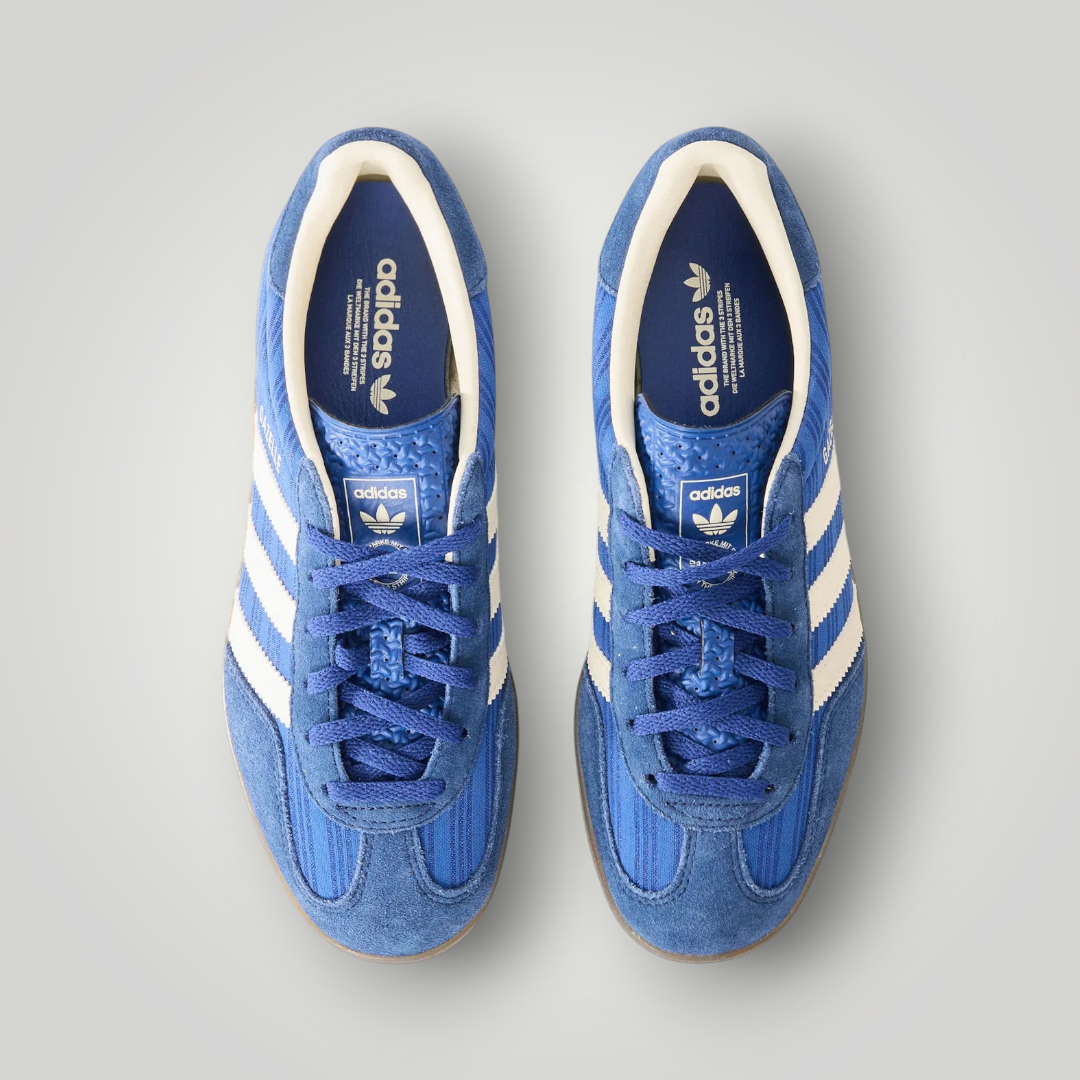 NDO Clothing adidas Originals Gazelle Indoor Sneaker in Blau mit weißen Streifen und flacher Gummisohle in Draufsicht